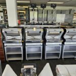 bakkerij machine kopen - Een rij nieuwe, ongebruikte handelspapiersnijders op de werkvloer van een bakkerijmachine. - theovanvliet.nl